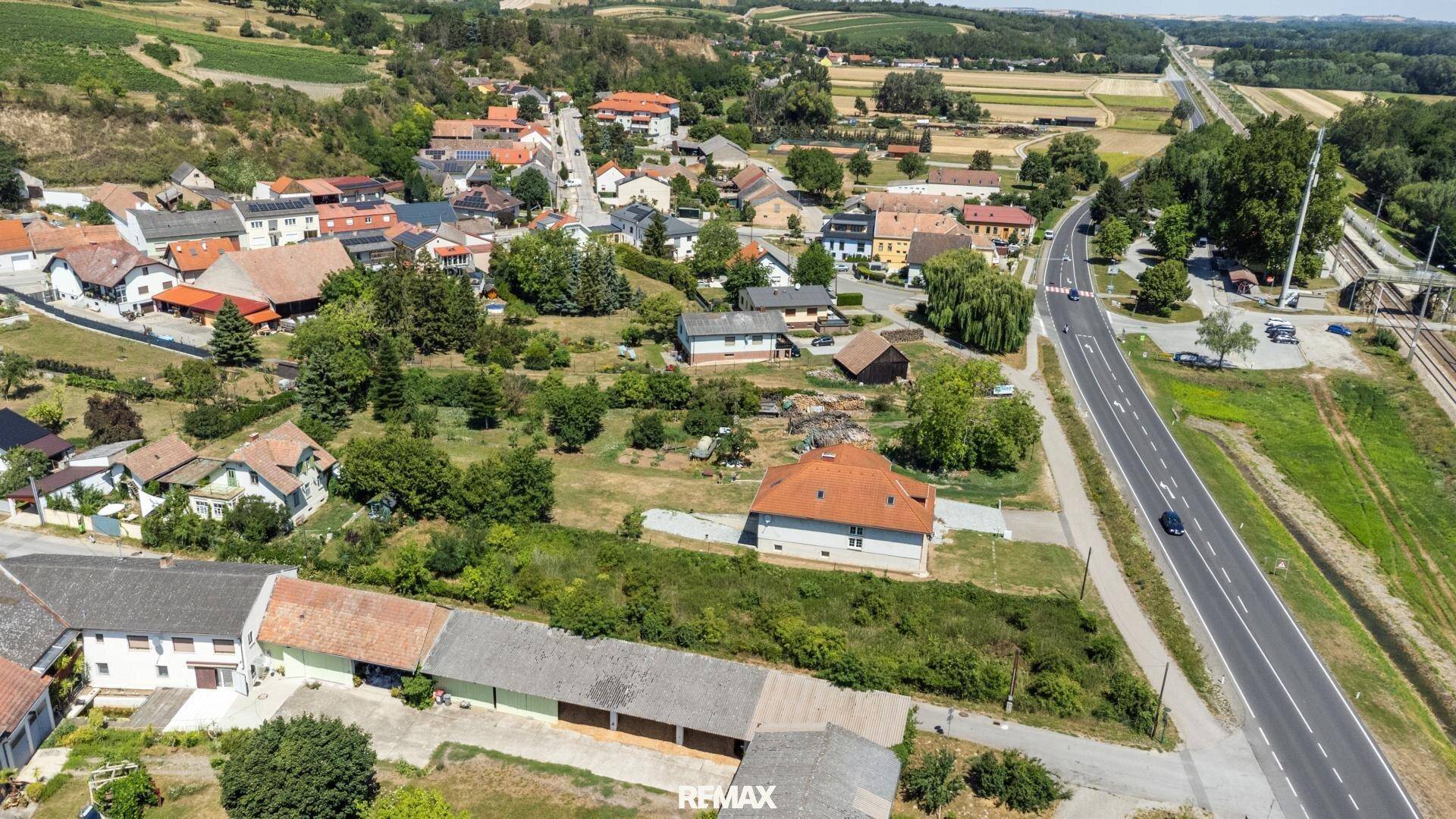Weitläufige Luftaufnahme einer ländlichen Siedlung mit Häusern, Straßen und grüner Umgebung.