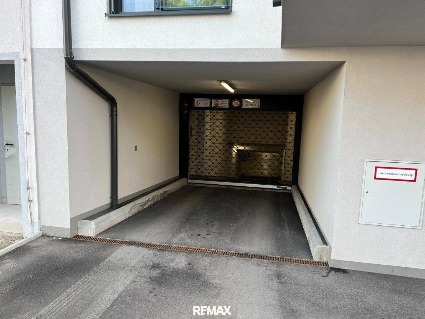 Einfahrt zur Tiefgarage eines modernen Wohnkomplexes mit Rolltor.