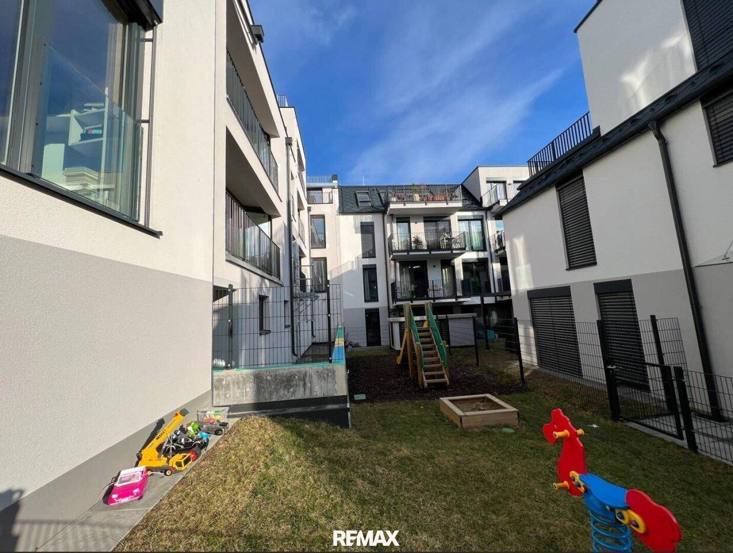 Gemeinschaftlicher Innenhof mit Spielplatz und Grünfläche, umgeben von modernen Wohngebäuden.