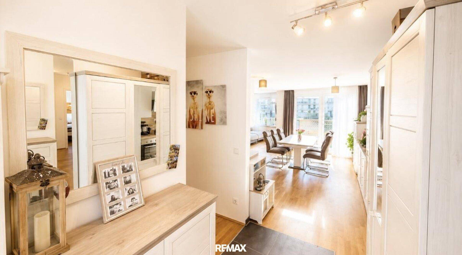 Heller Eingangsbereich mit Garderobe, Spiegel und Blick in den offenen Wohn-Essbereich.