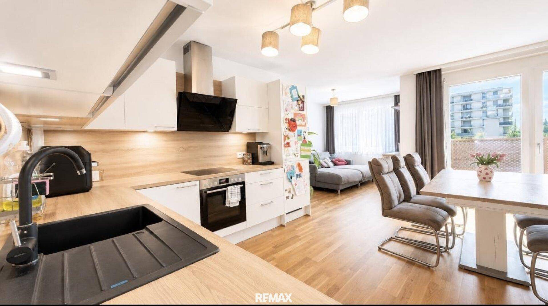 Geräumiger offener Wohn-Essbereich mit integrierter Küche und Zugang zum Balkon.