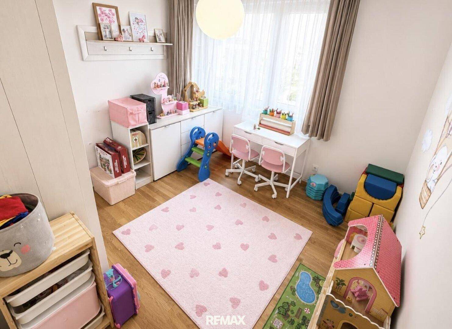 Helles Kinderzimmer mit Spielbereich, kleinem Schreibtisch und viel Platz zum Spielen.