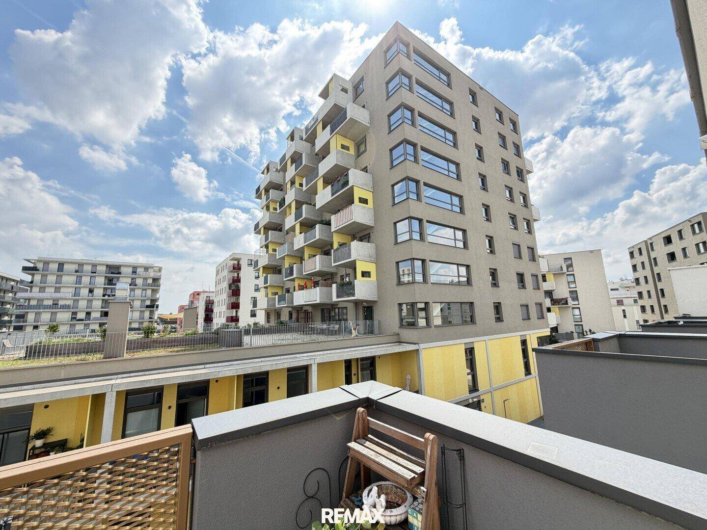 Moderne Wohngebäude in einer Siedlung, gesehen von einem Balkon unter blauem Himmel.