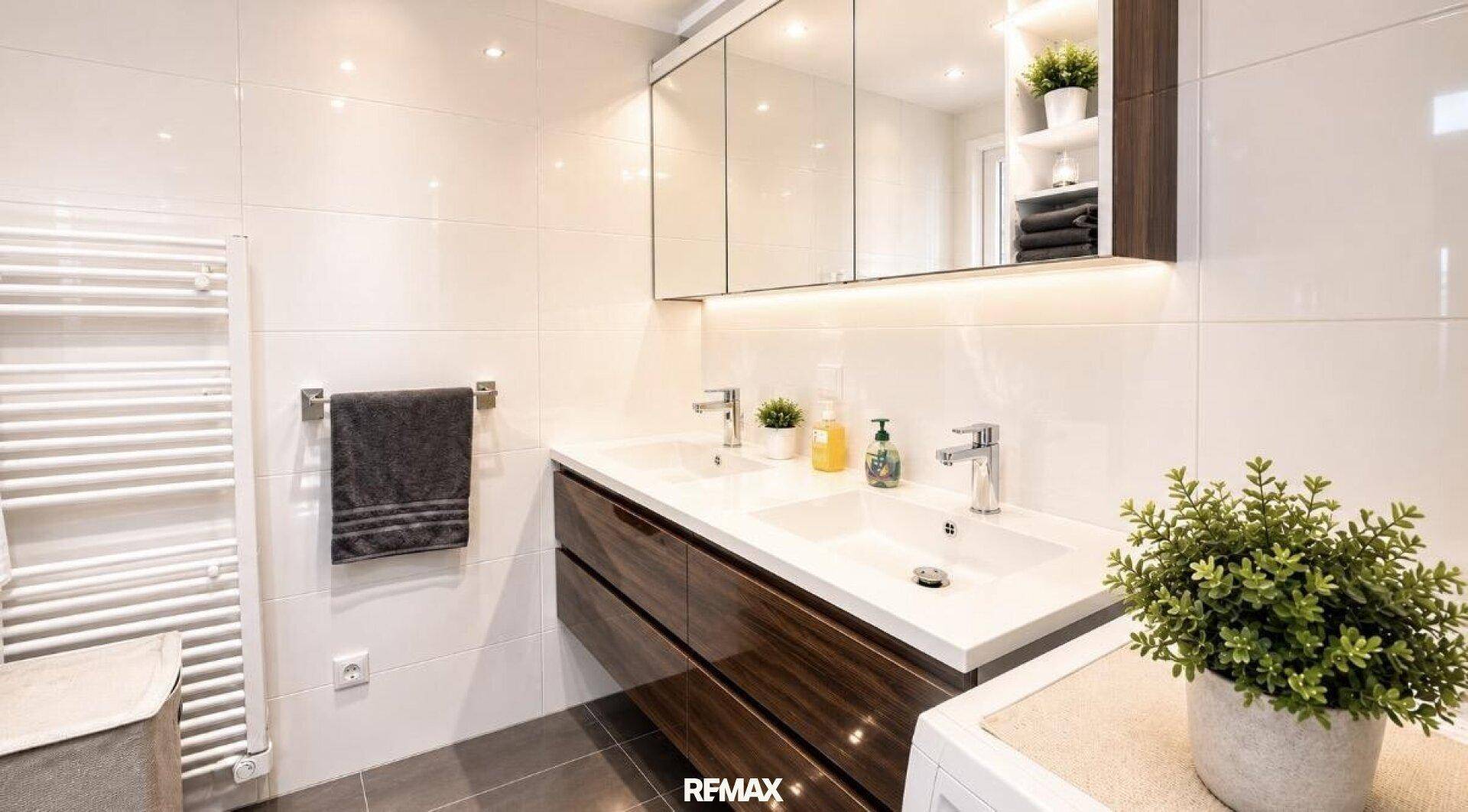 Modernes Badezimmer mit Doppelwaschbecken, Spiegelschrank und weißen Fliesen.