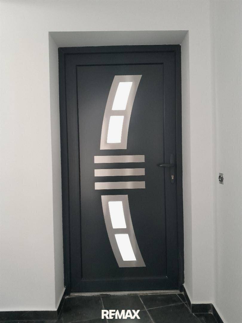 Moderne Eingangstür in Dunkelgrau mit stilvollen silbernen Designelementen.