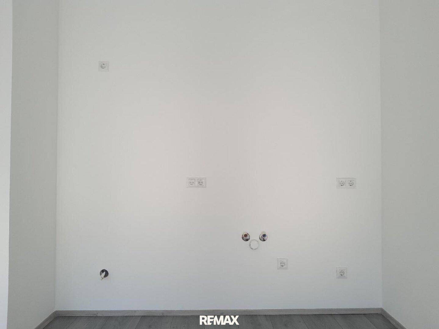 Vorbereitete Wand für eine Küche mit zahlreichen Steckdosen und Wasseranschlüssen.