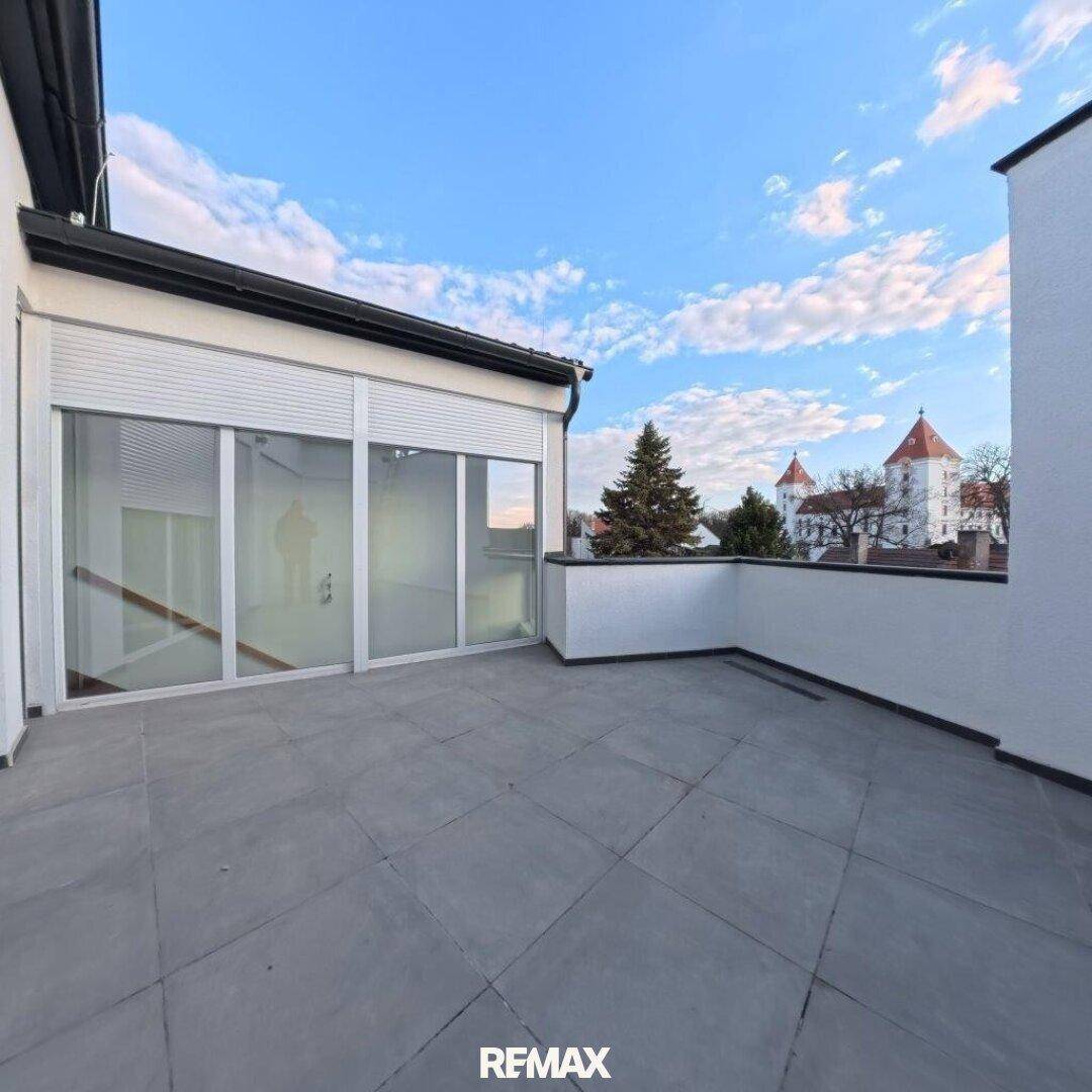 Große Dachterrasse mit Fliesenboden und Blick auf die umliegende Stadt.