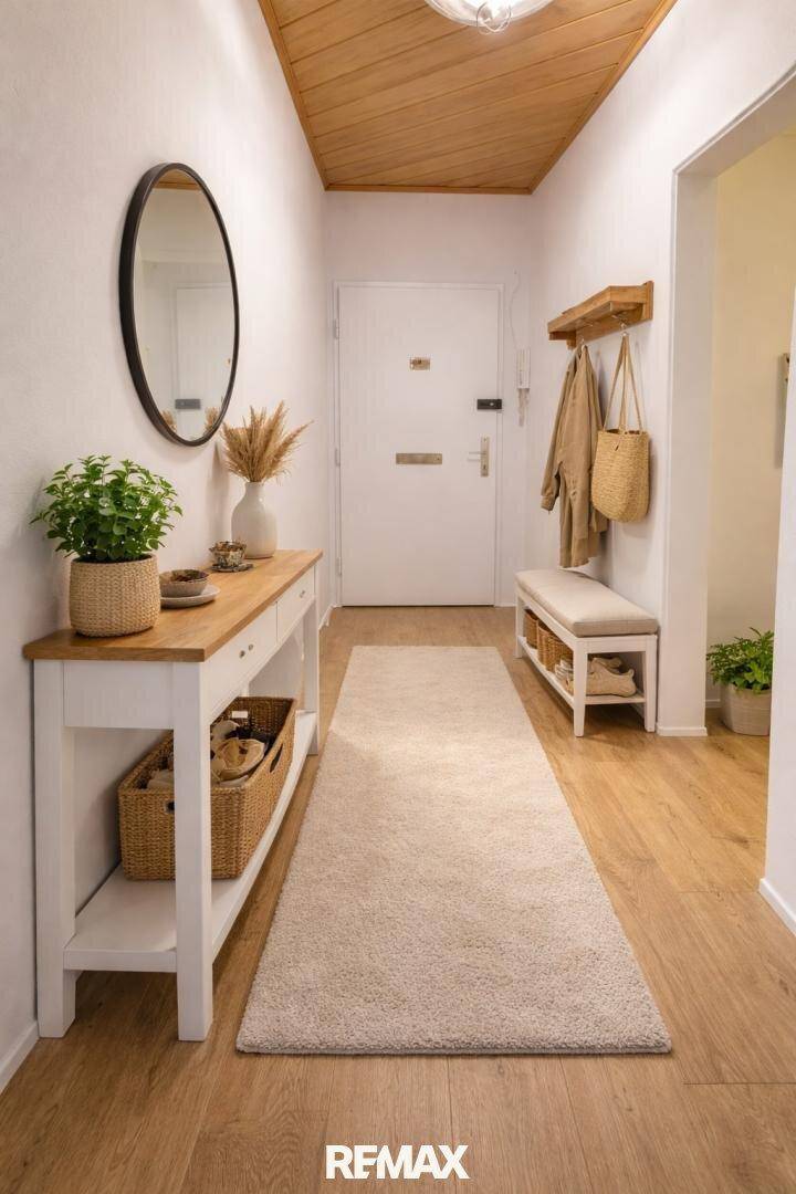 Heller Flur mit Holzboden, Garderobe und einem Spiegel, der den Raum erweitert.