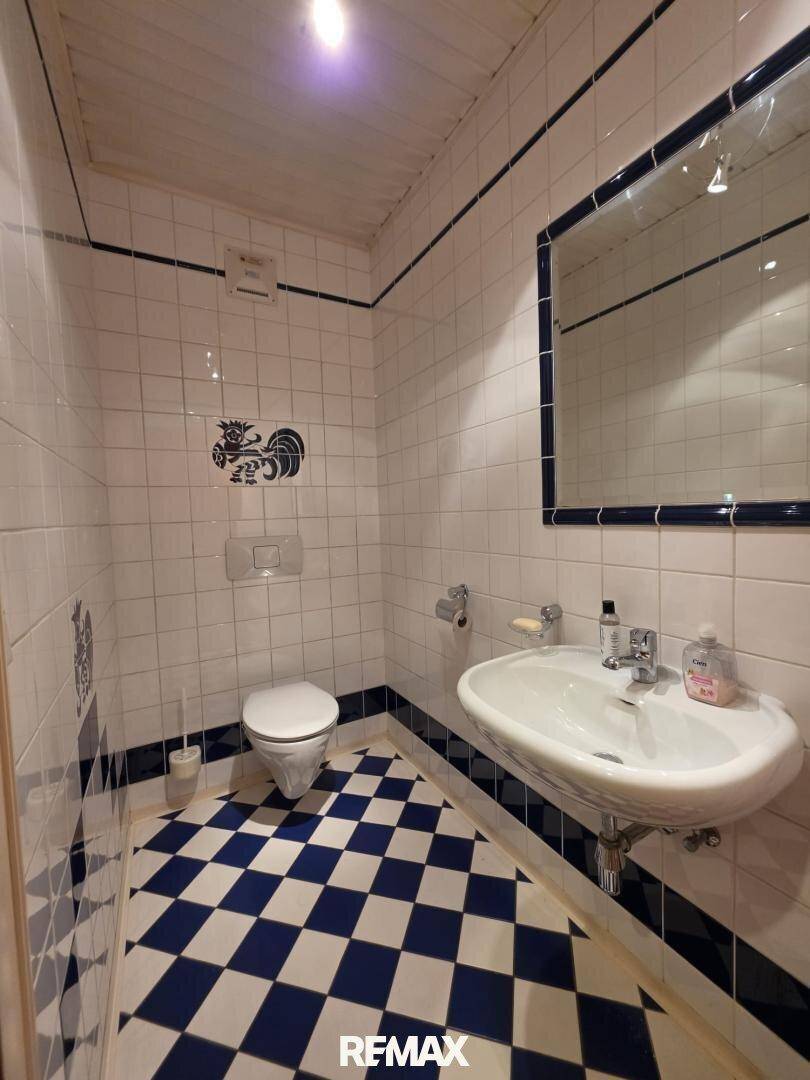 Kleines Gäste-WC mit blau-weiß kariertem Fliesenboden und Wandfliesen.