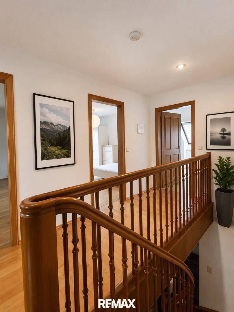 Heller Flur im Obergeschoss mit Holzgeländer und Blick in angrenzende Zimmer.