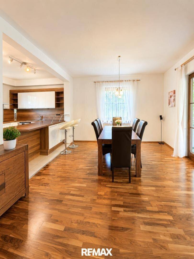 Offener Wohn- und Essbereich mit Holzboden, großem Esstisch und Zugang zur Terrasse.