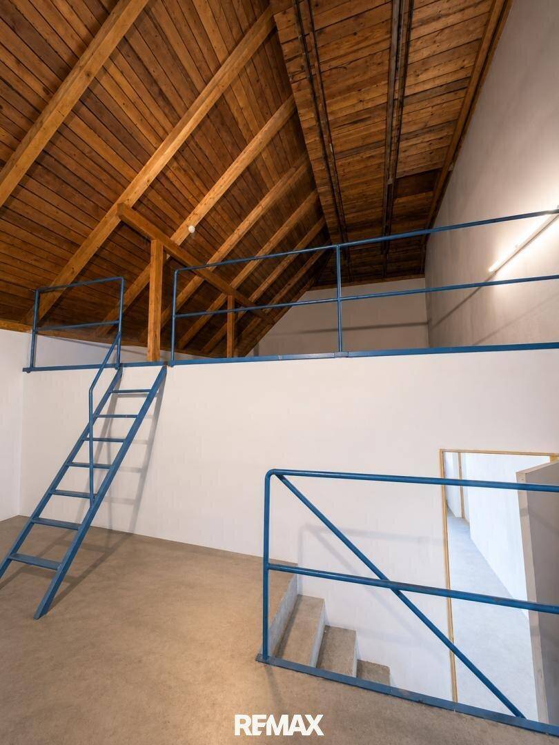 Ausbaufähiger Dachboden mit sichtbaren Holzbalken und einer blauen Metalltreppe.