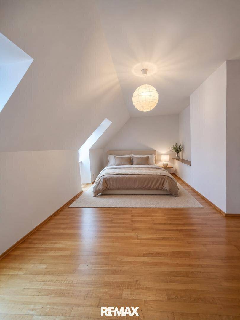 Gemütliches Schlafzimmer im Dachgeschoss mit Doppelbett, Dachschräge und Holzboden.