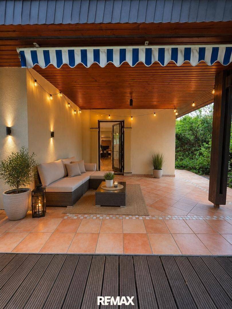 Überdachte Terrasse mit gemütlicher Sitzecke, Lichterkette und Terracotta-Fliesen.