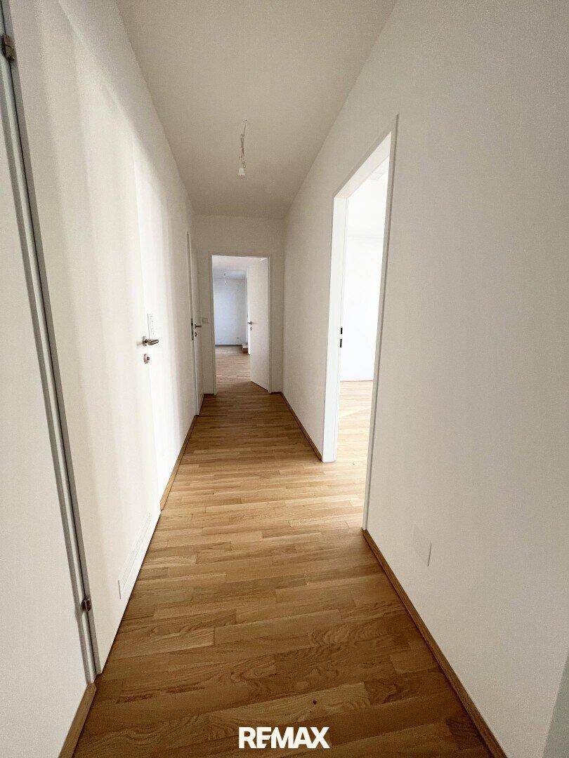 Langer, heller Flur mit Holzboden und mehreren Türen, verbindet die verschiedenen Räume der Wohnung.