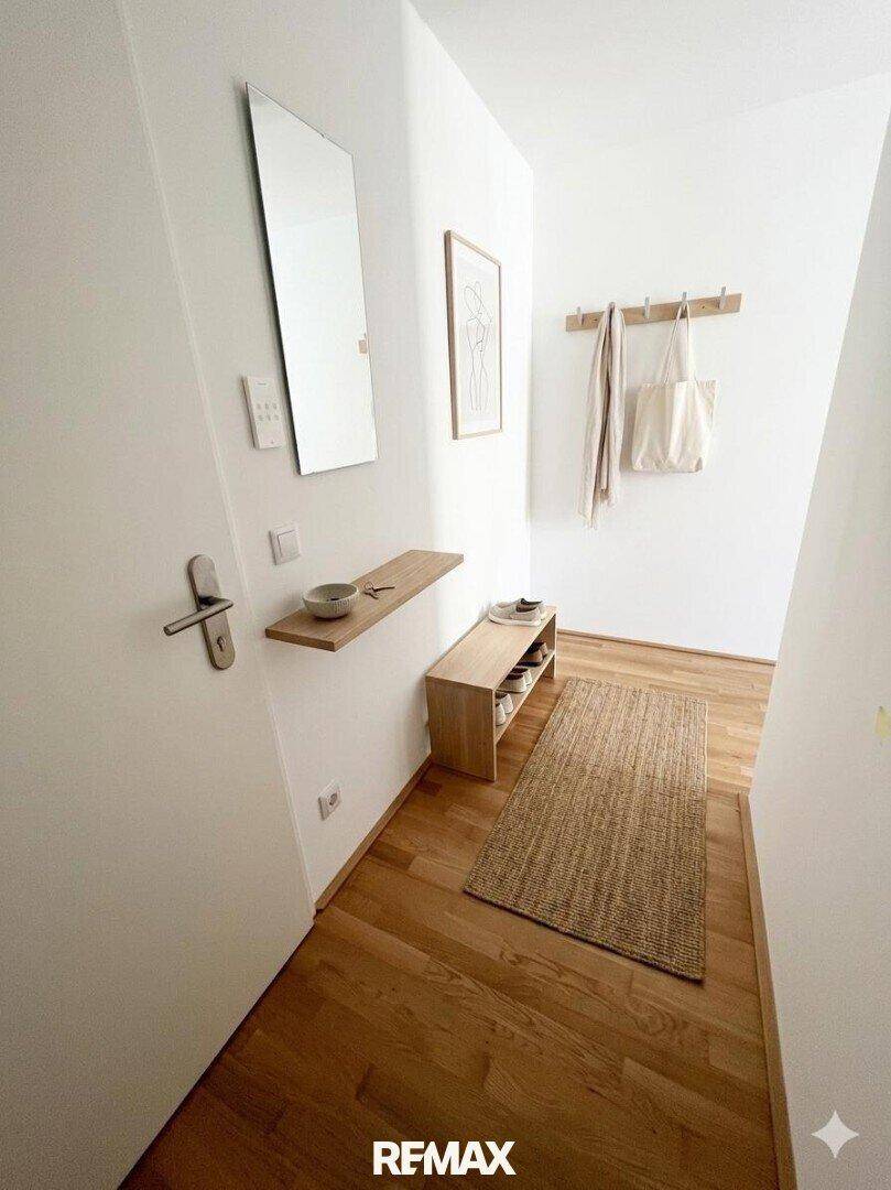 Heller Eingangsbereich mit Holzboden, Spiegel und Garderobe, modern und funktional gestaltet.