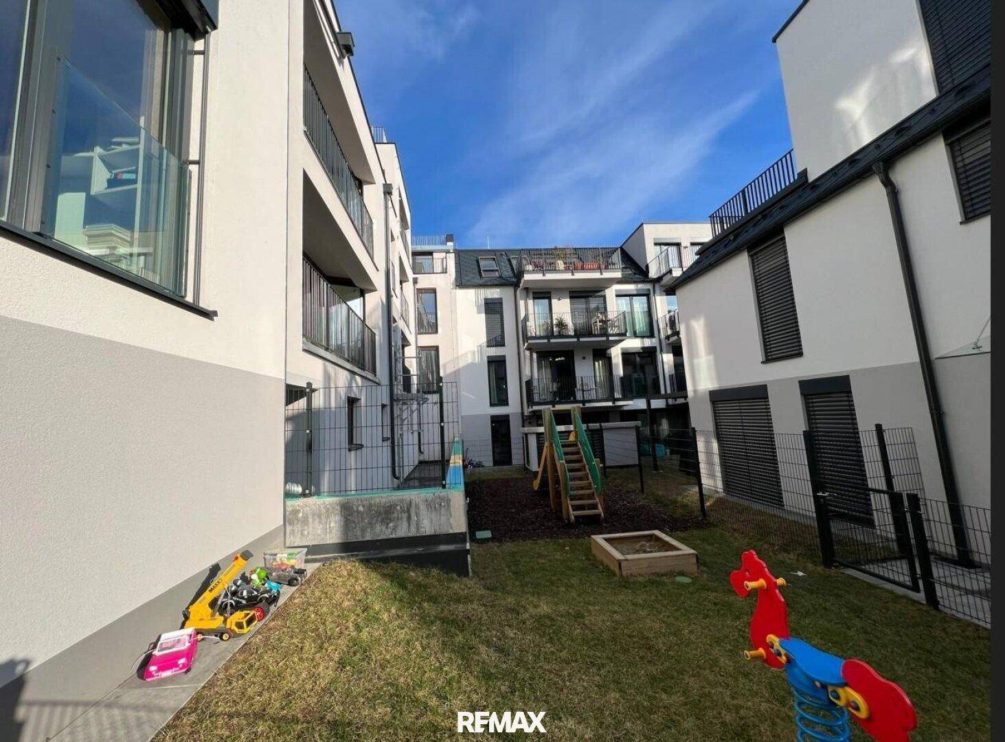 Innenhof mit Kinderspielplatz und umliegenden modernen Wohngebäuden, bietet Raum für Familien.