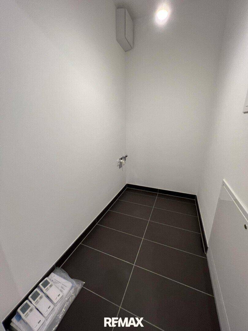 Kleiner Hauswirtschaftsraum mit Fliesenboden und Anschlüssen, ideal für Waschmaschine oder Abstellfläche.