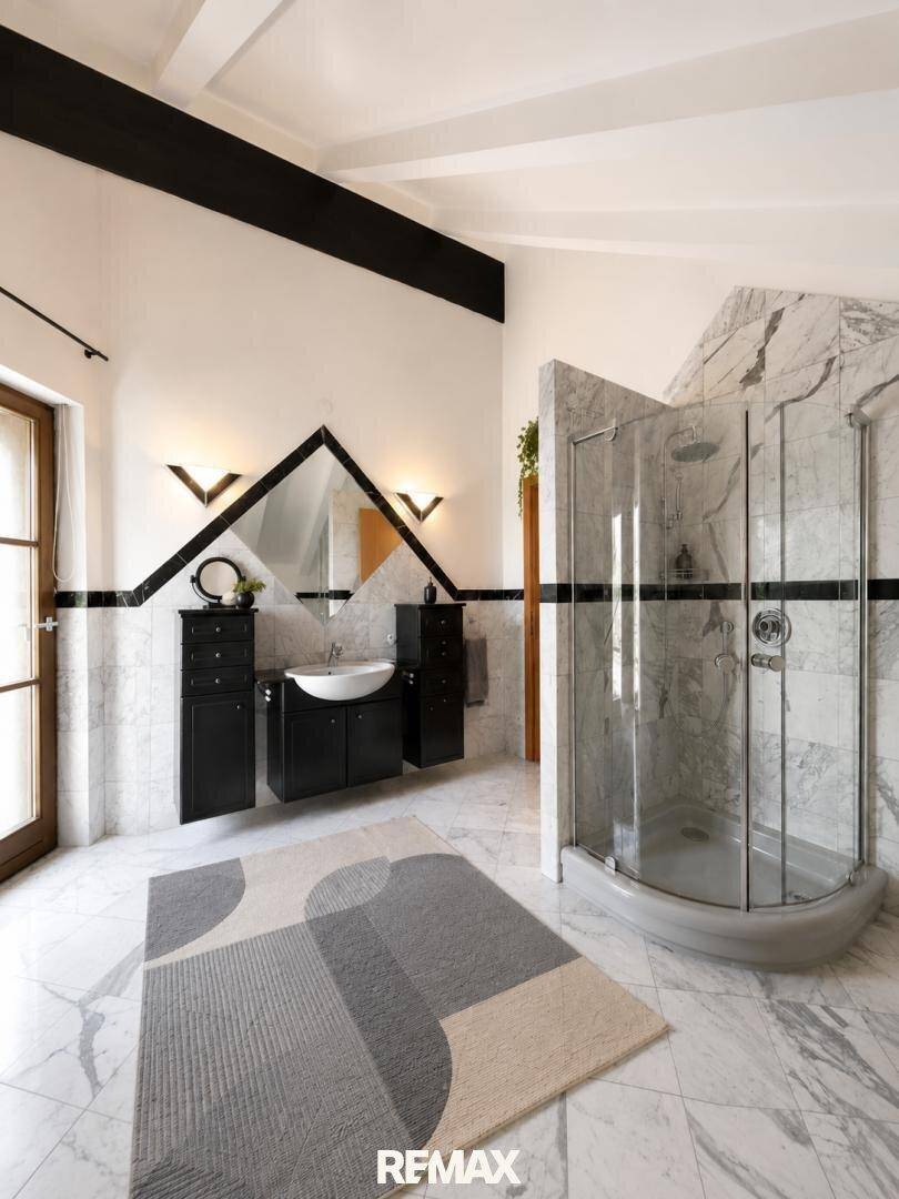 Modernes Badezimmer mit Marmorfliesen, Duschkabine und Einzelwaschbecken.