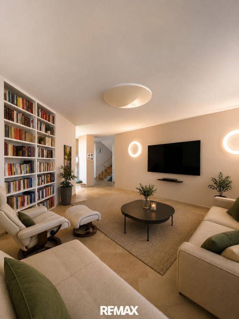 Modernes Wohnzimmer mit großem Bücherregal, bequemen Sofas und Fernseher.