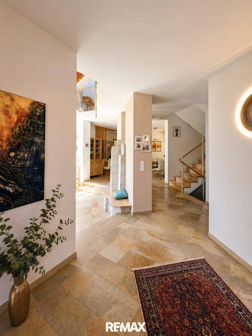 Heller Eingangsbereich mit Steinboden, Teppich und Blick auf weitere Wohnbereiche und Treppe.