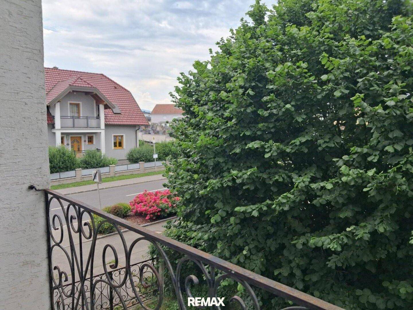 Balkon mit schmiedeeisernem Geländer und Blick auf die Straße und umliegende Häuser.