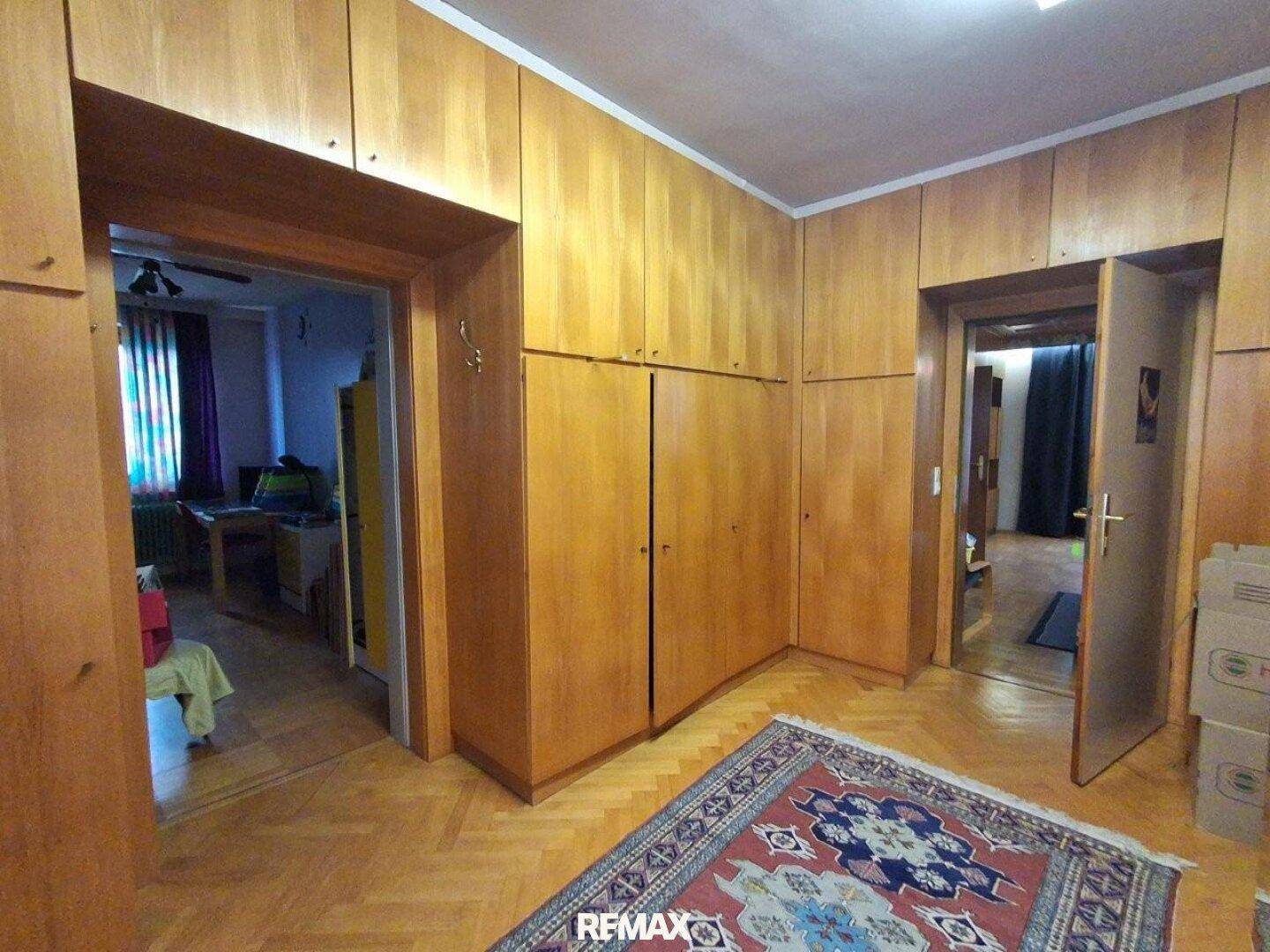 Flur mit Einbauschränken aus Holz und Parkettboden, der zu weiteren Räumen führt.