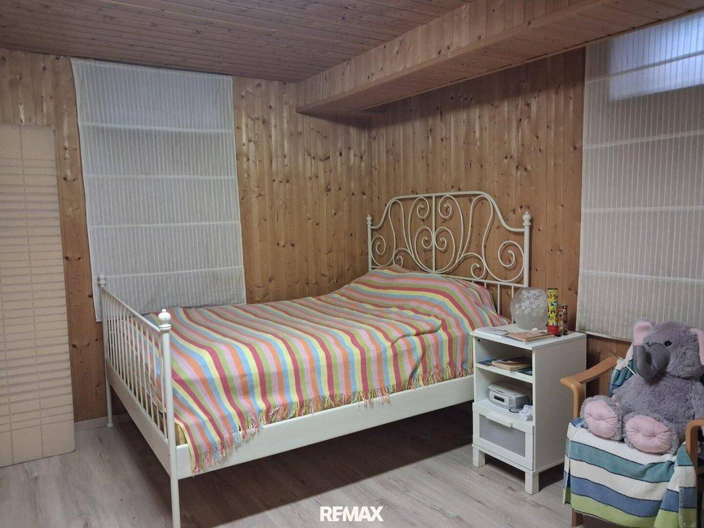 Schlafzimmer mit Holztäfelung an Wänden und Decke, sowie einem schmiedeeisernen Bett.