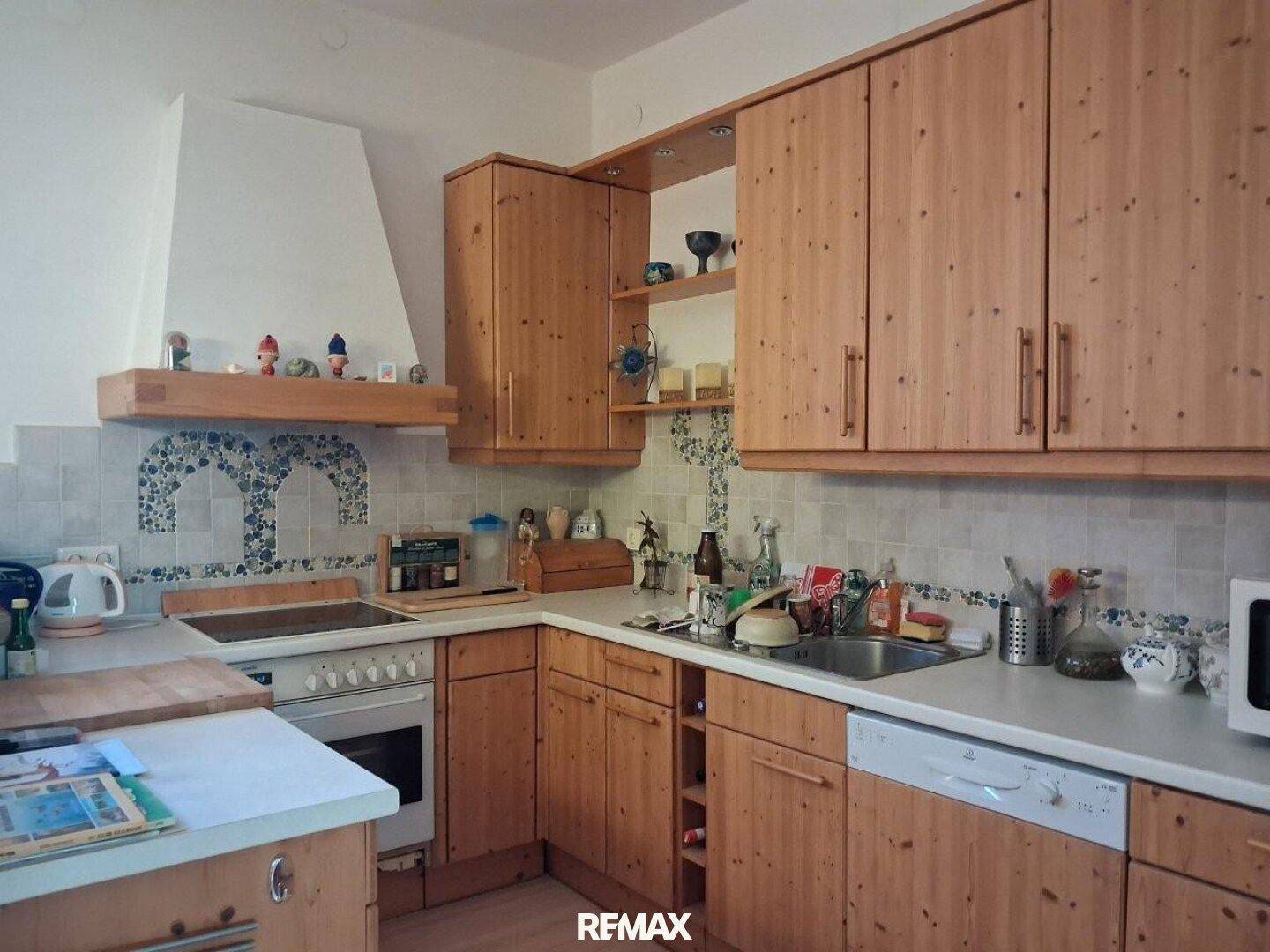 Rustikale Einbauküche aus hellem Holz mit integrierten Geräten und gefliestem Spritzschutz.