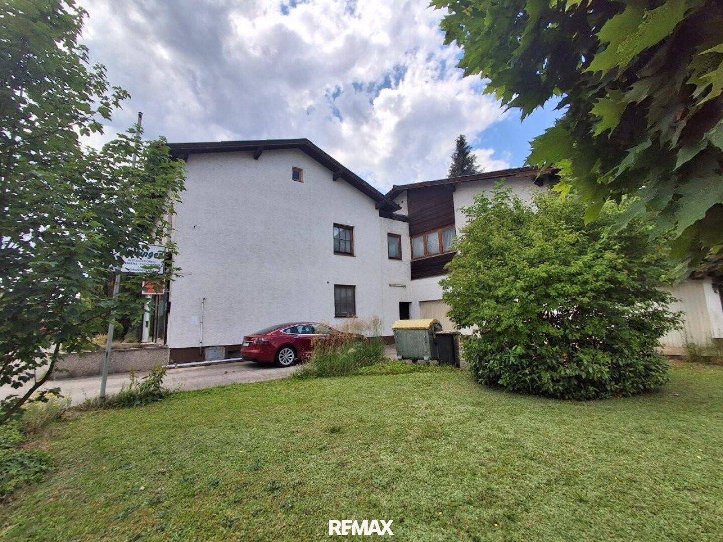 Hinteransicht des Hauses mit großem Rasenbereich und Bäumen im Garten.