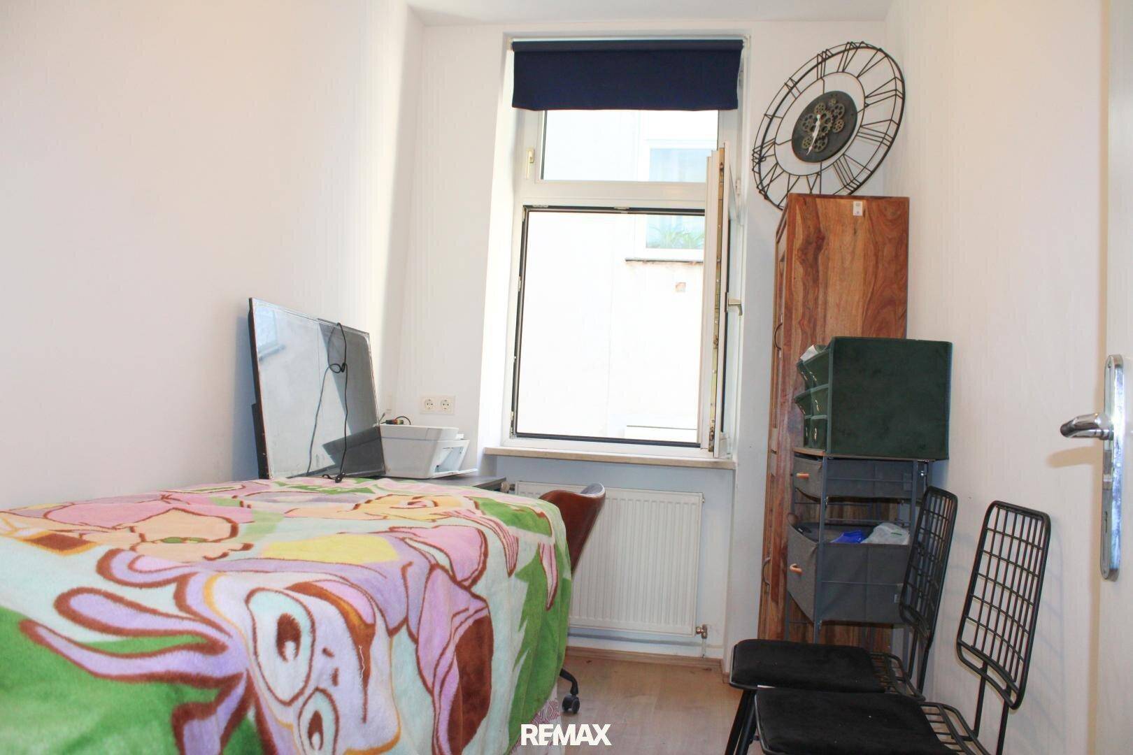Kleines Schlafzimmer mit Einzelbett, Schreibtisch und einem Fenster.