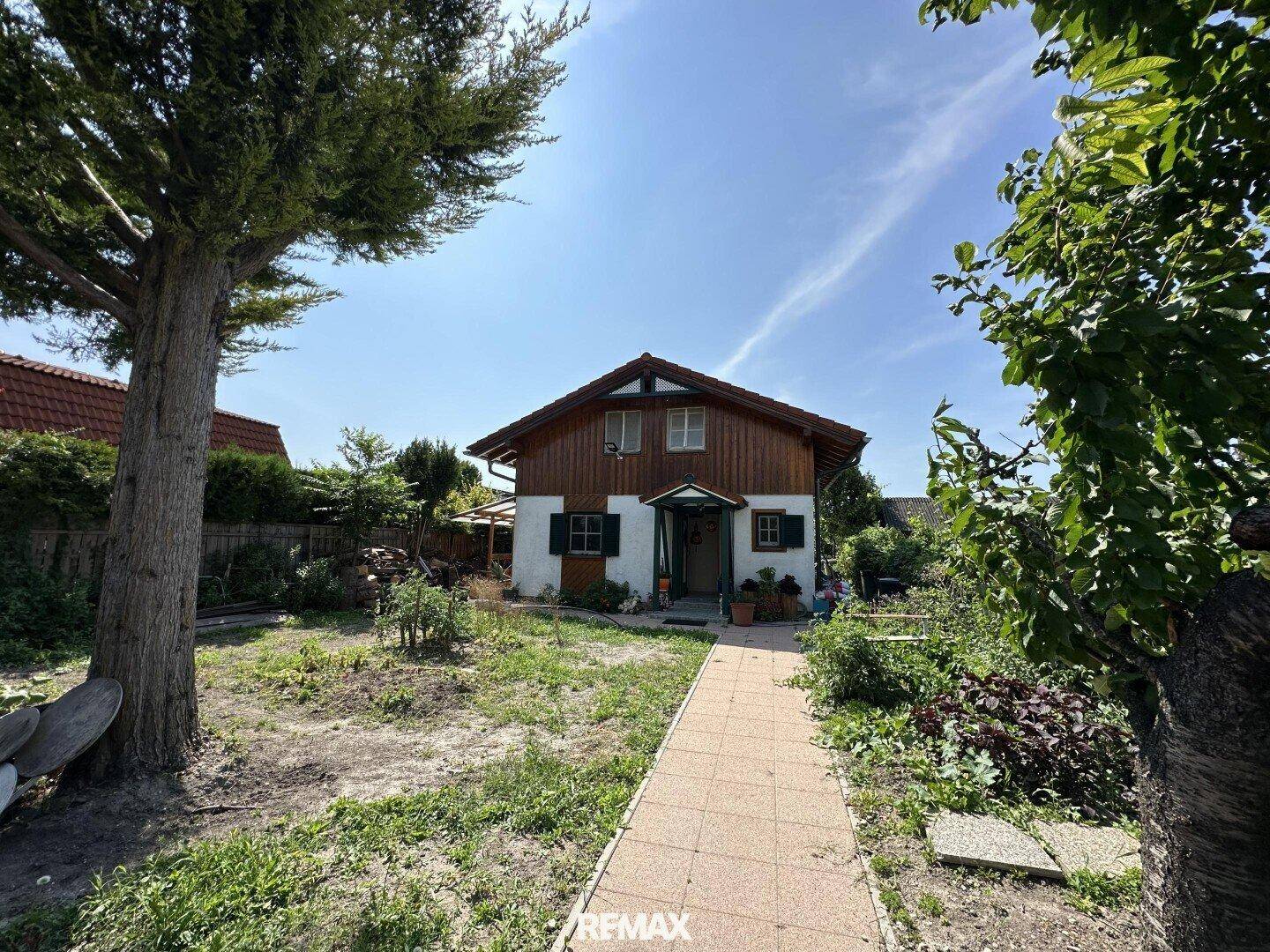 Vorderansicht des Hauses mit Gartenweg, Bäumen und viel Grün.