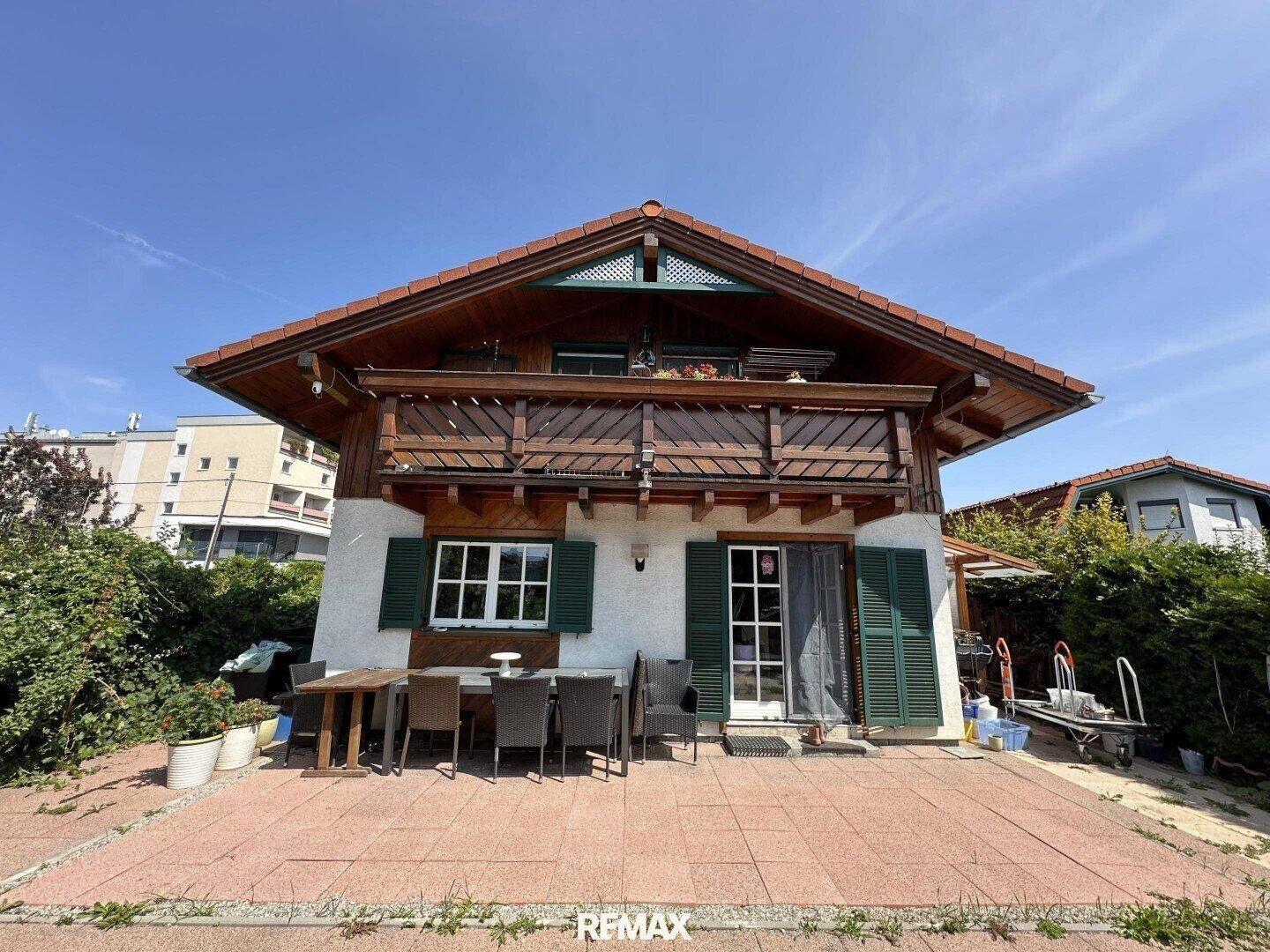 Rückseite des Hauses mit großer gepflasterter Terrasse und Essbereich im Freien.