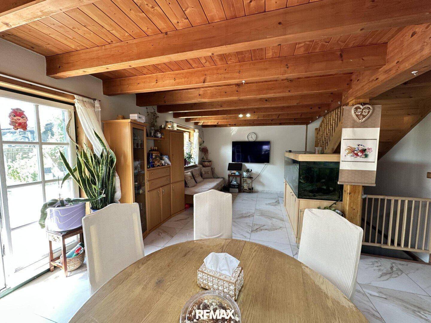Gemütlicher Wohn- und Essbereich mit Holzbalkendecke, großem Aquarium und Zugang zur Terrasse.