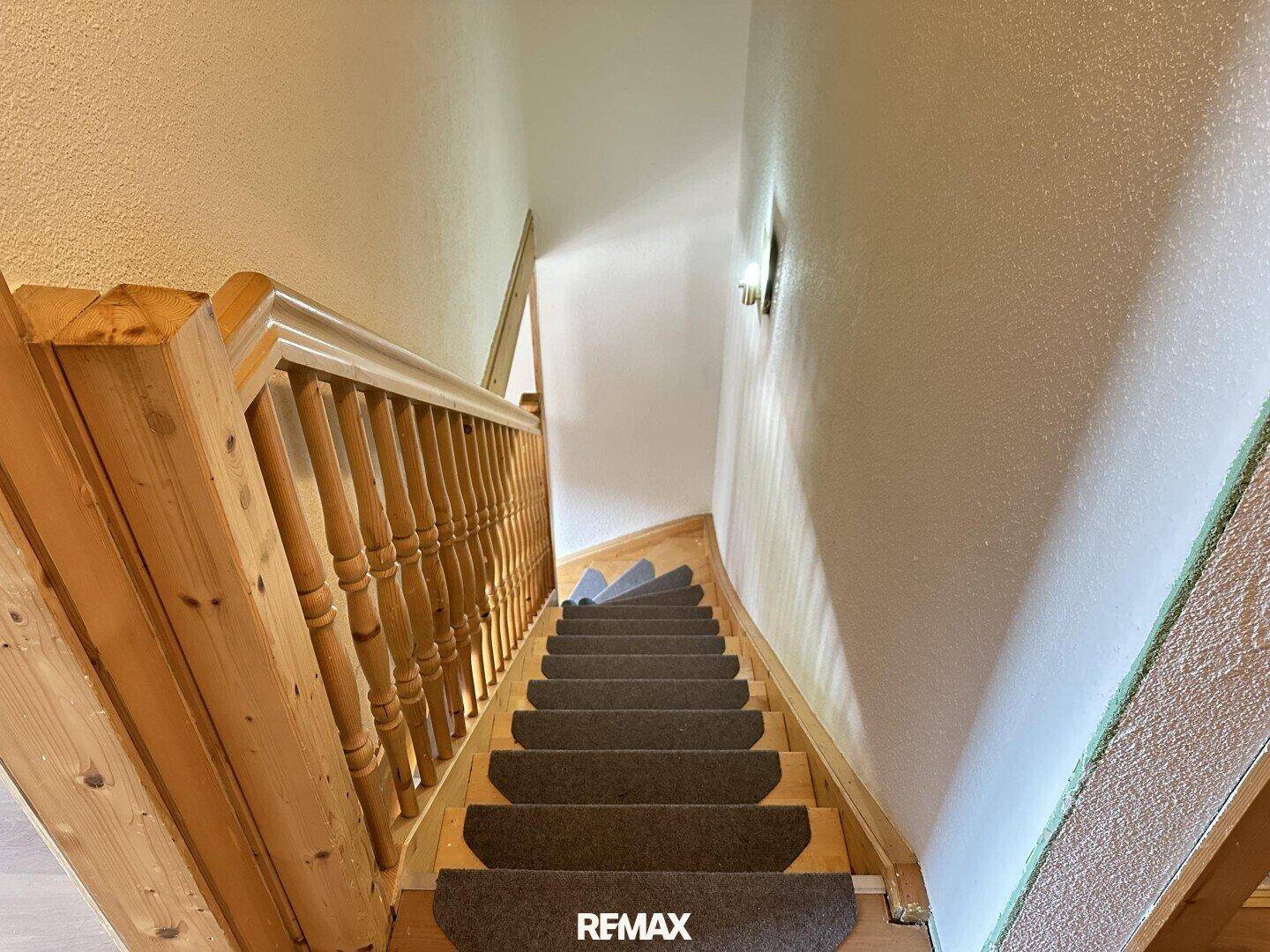 Holztreppe mit Teppichstufen, die in das obere Stockwerk des Hauses führt.