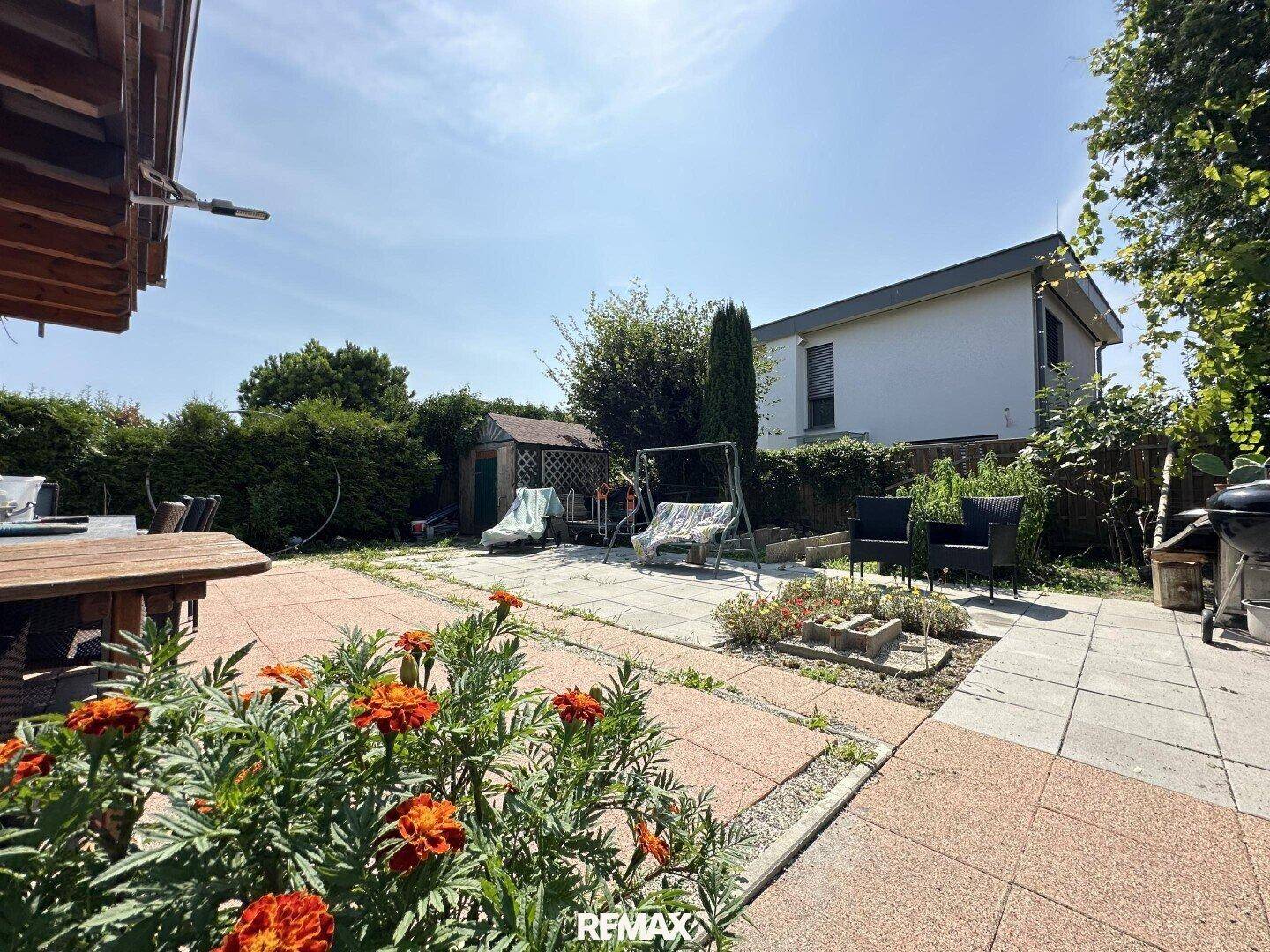 Großer Garten mit gepflasterter Terrasse, Gartenhaus und verschiedenen Sitzgelegenheiten.