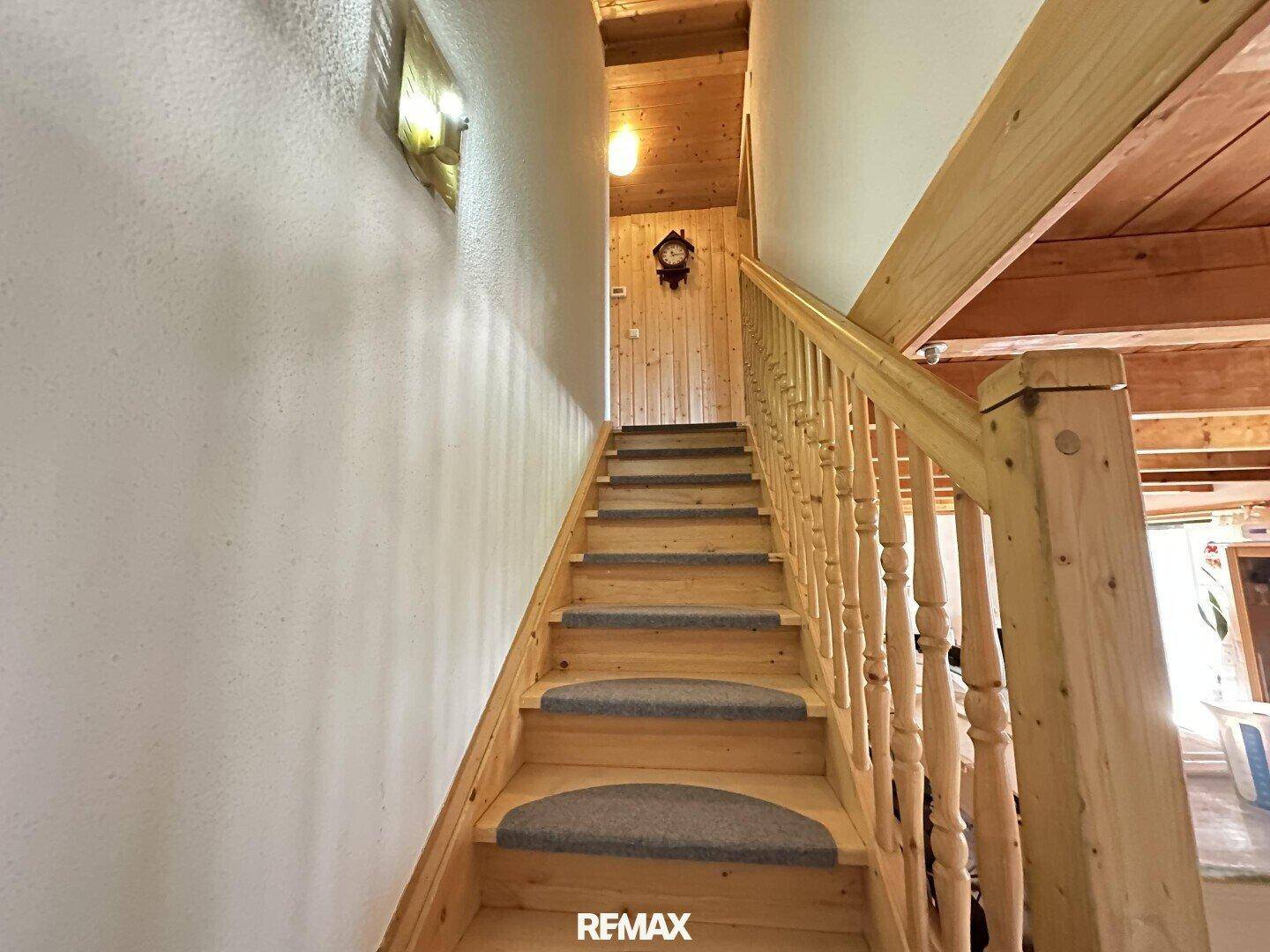 Holztreppe mit Teppichstufen, die in das obere Stockwerk des Hauses führt.