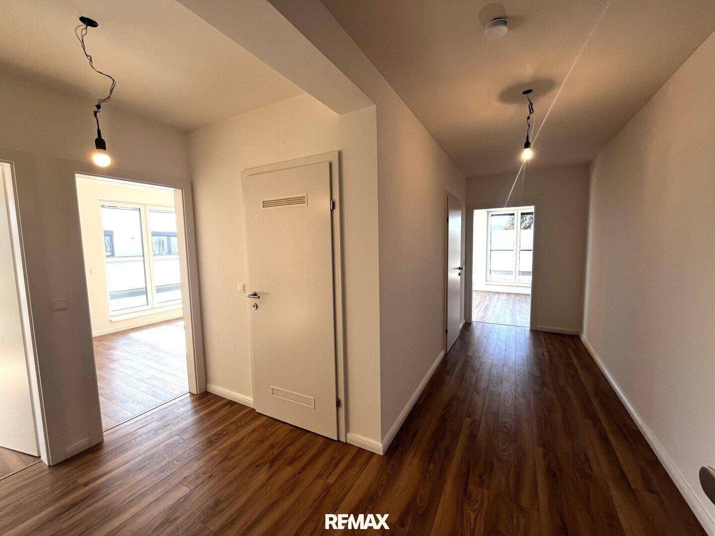 Heller Flur mit Laminatboden und Zugang zu mehreren Zimmern in der Wohnung.