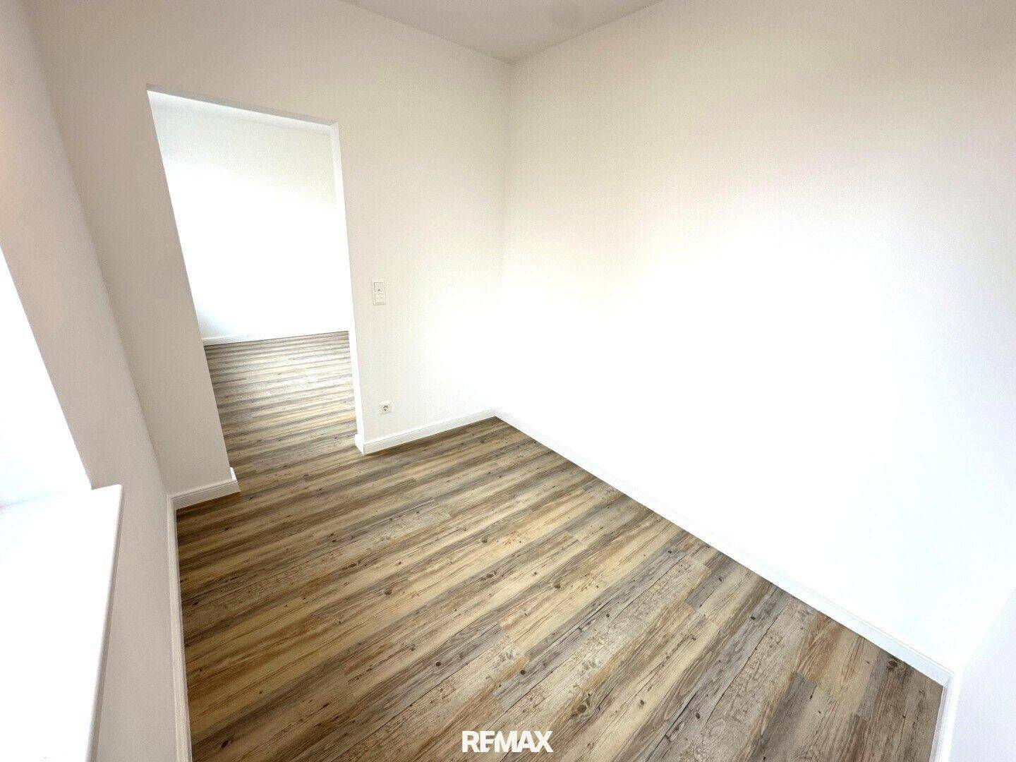 Kleinerer, heller Raum mit Laminatboden und weißen Wänden, ideal als Büro oder Gästezimmer.