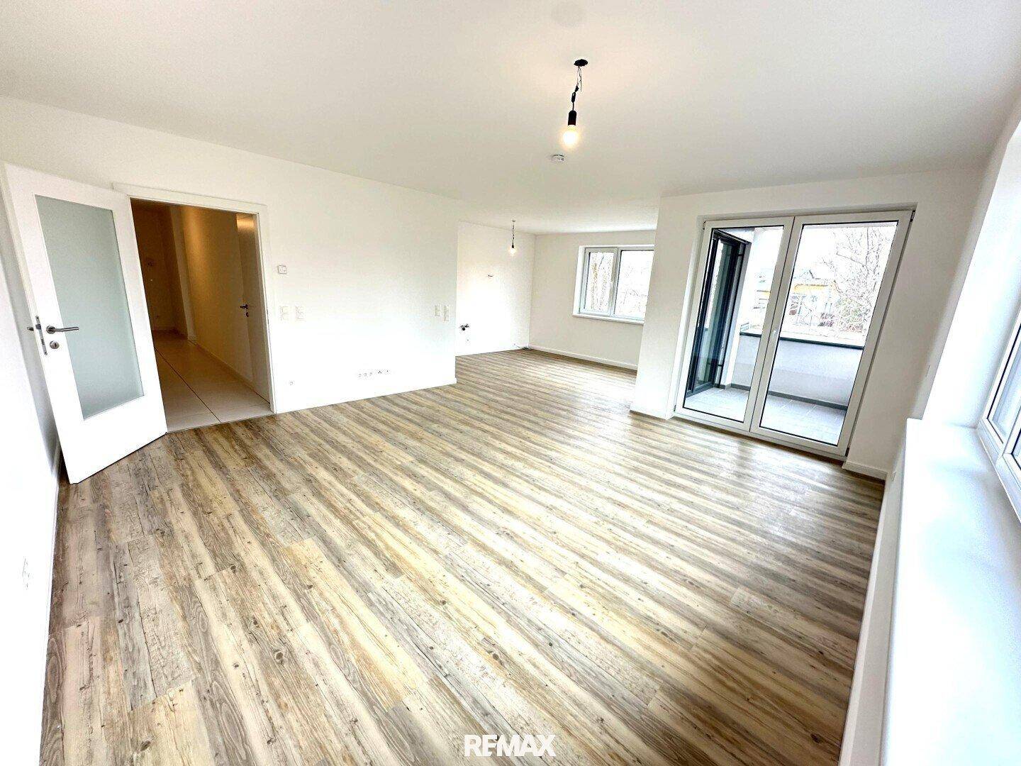Heller, leerer Raum mit modernem Laminatboden und Zugang zu einem Balkon.