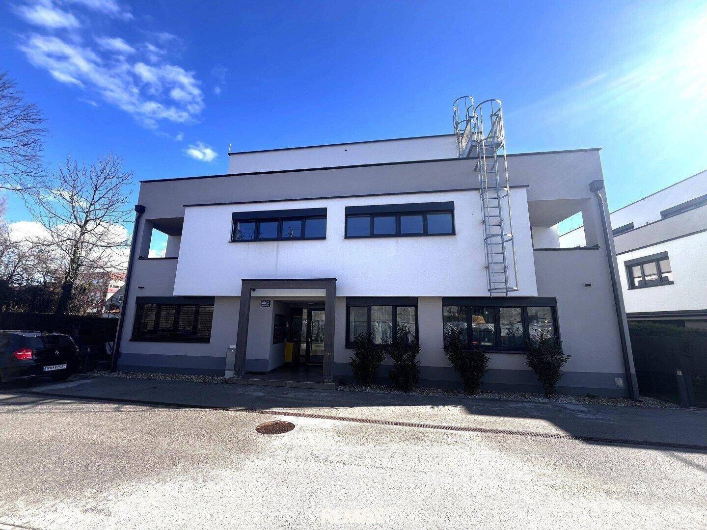 Moderne Fassade eines Neubaus mit klaren Linien und mehreren Fenstern.