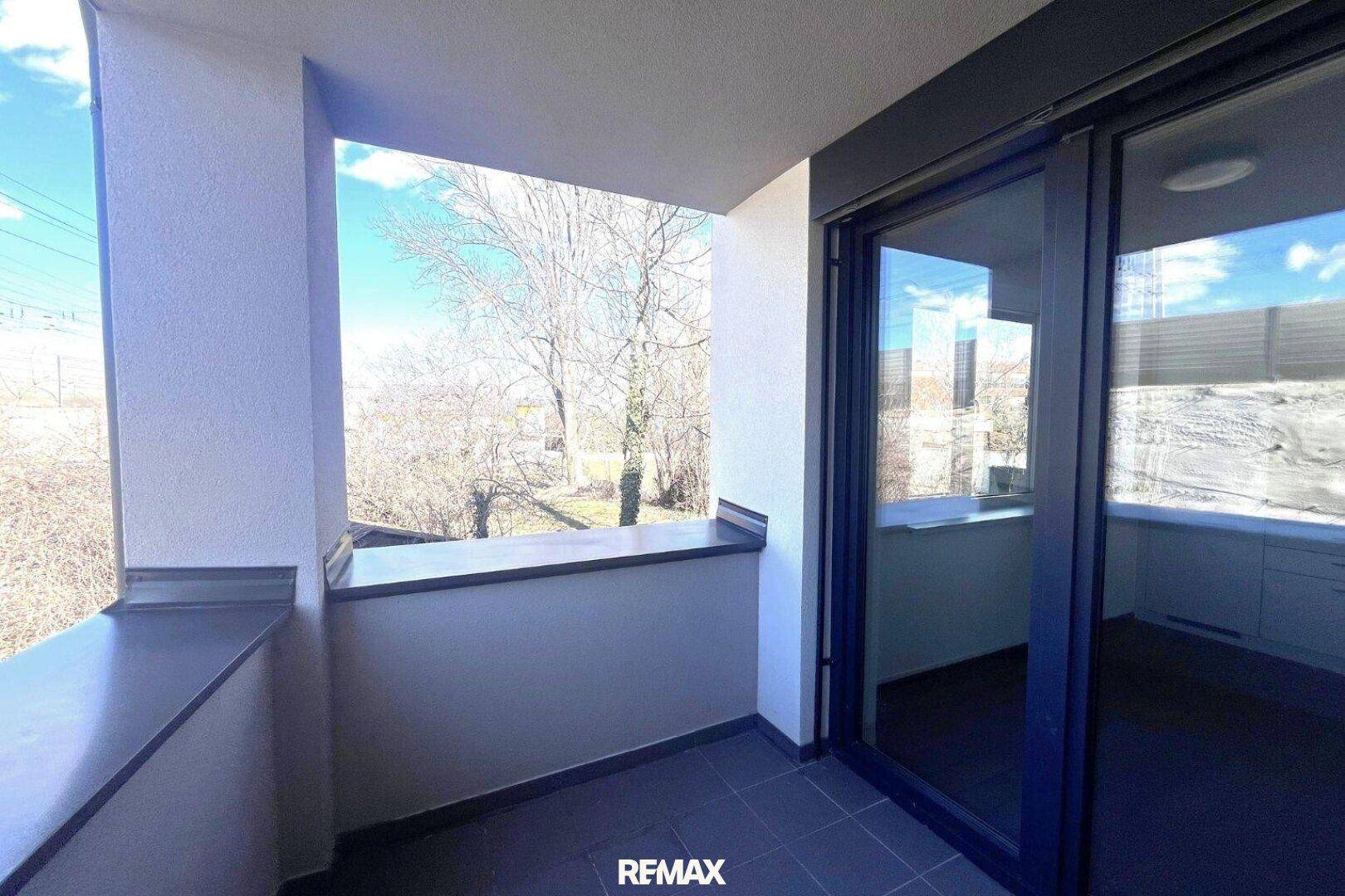 Heller Balkon mit Blick ins Grüne, ideal für entspannte Stunden im Freien.