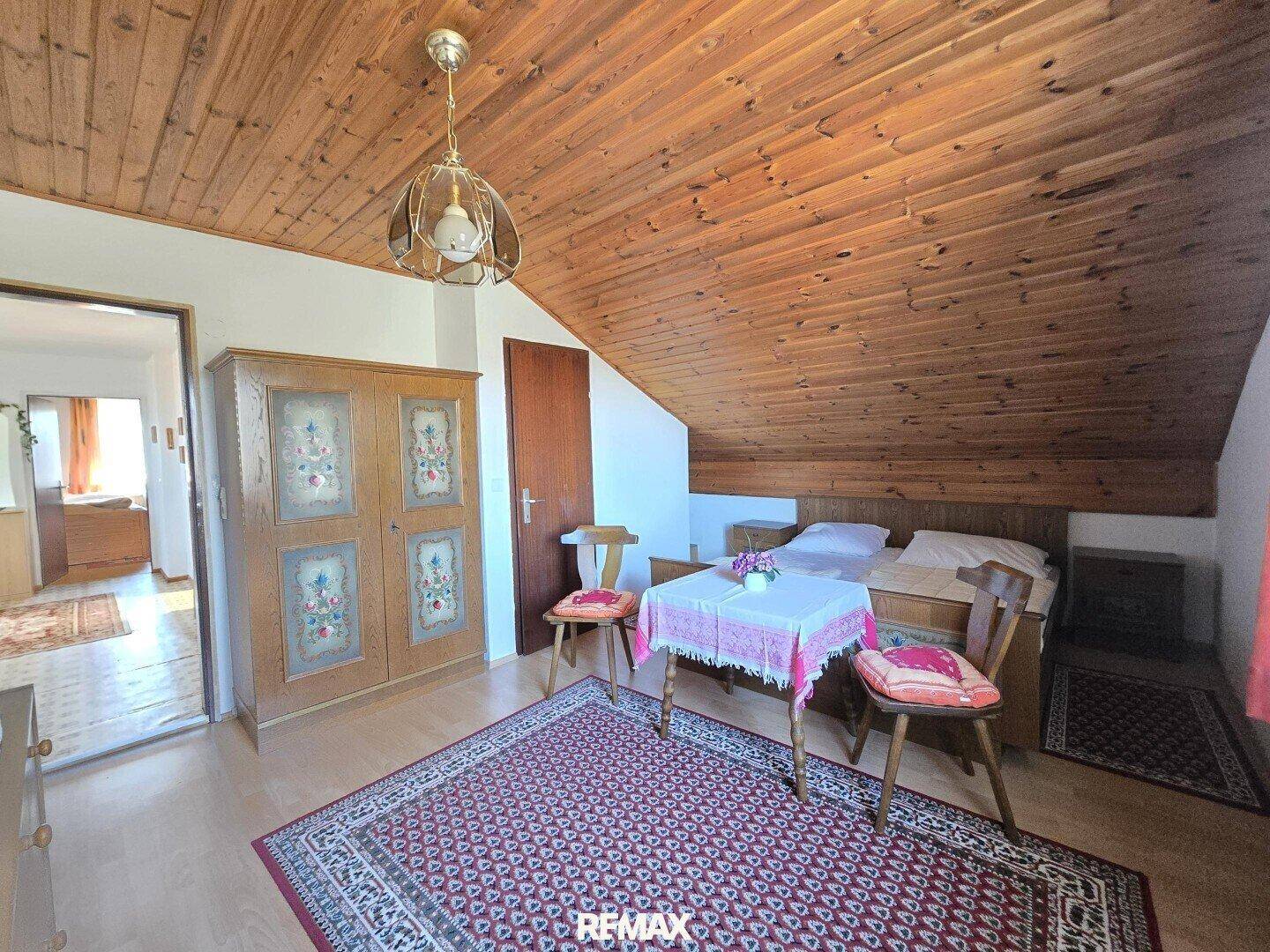 Gemütliches Schlafzimmer im Dachgeschoss mit Holzbalkendecke und traditionellen Möbeln.