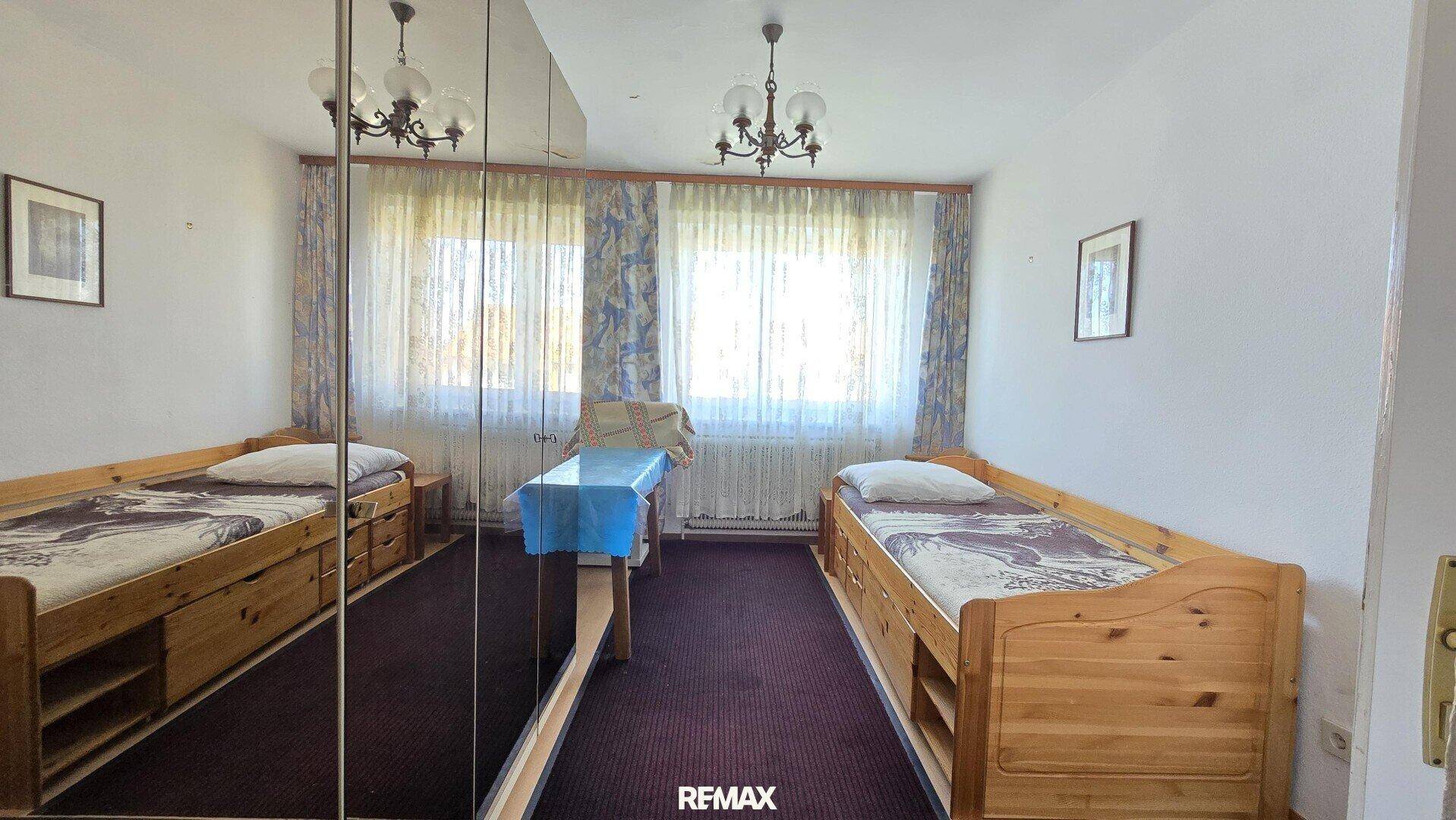 Schlafzimmer mit zwei Einzelbetten, Spiegelschrank und Teppichboden.