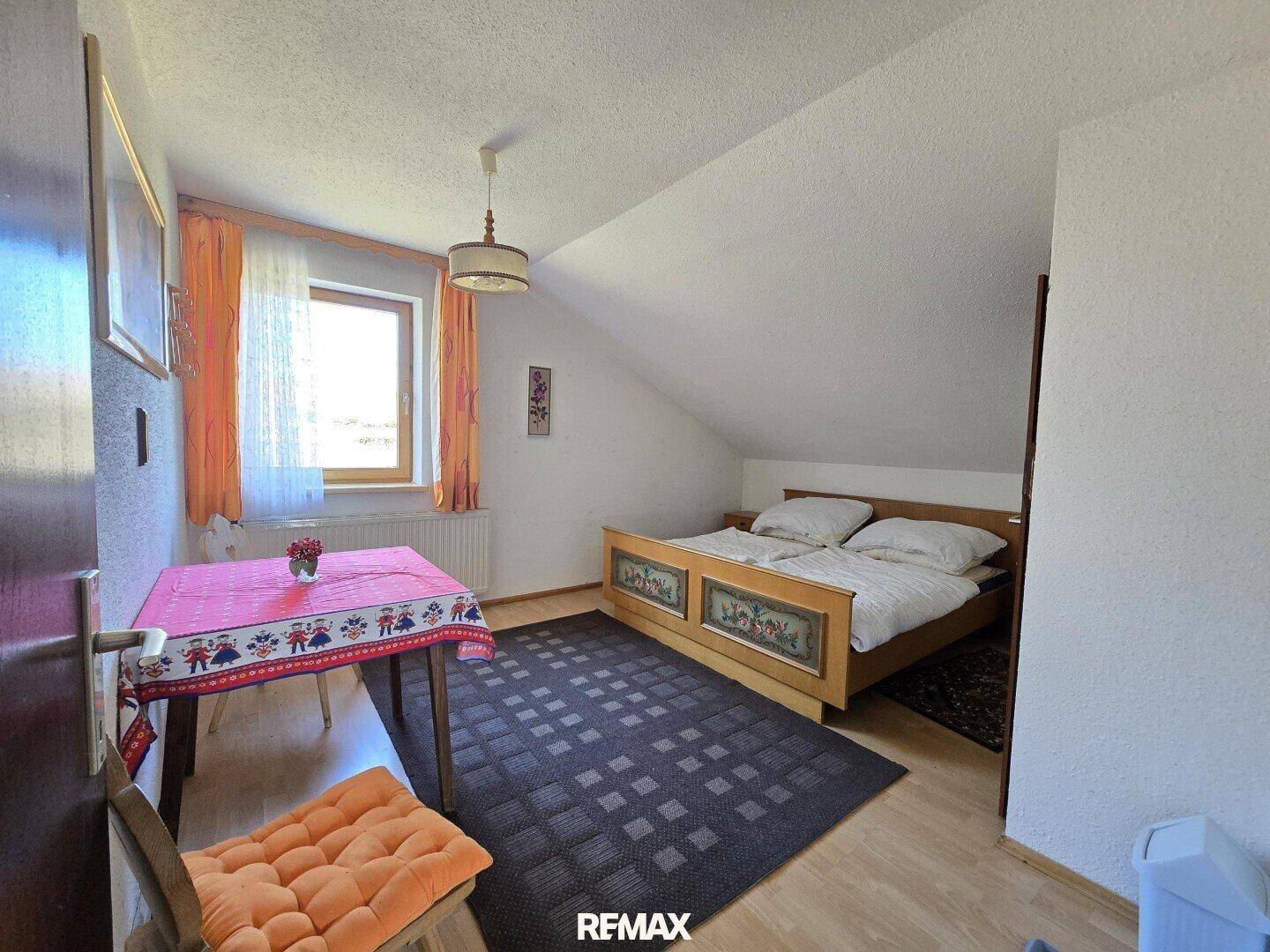 Helles Schlafzimmer im Dachgeschoss mit Doppelbett und Holzboden.