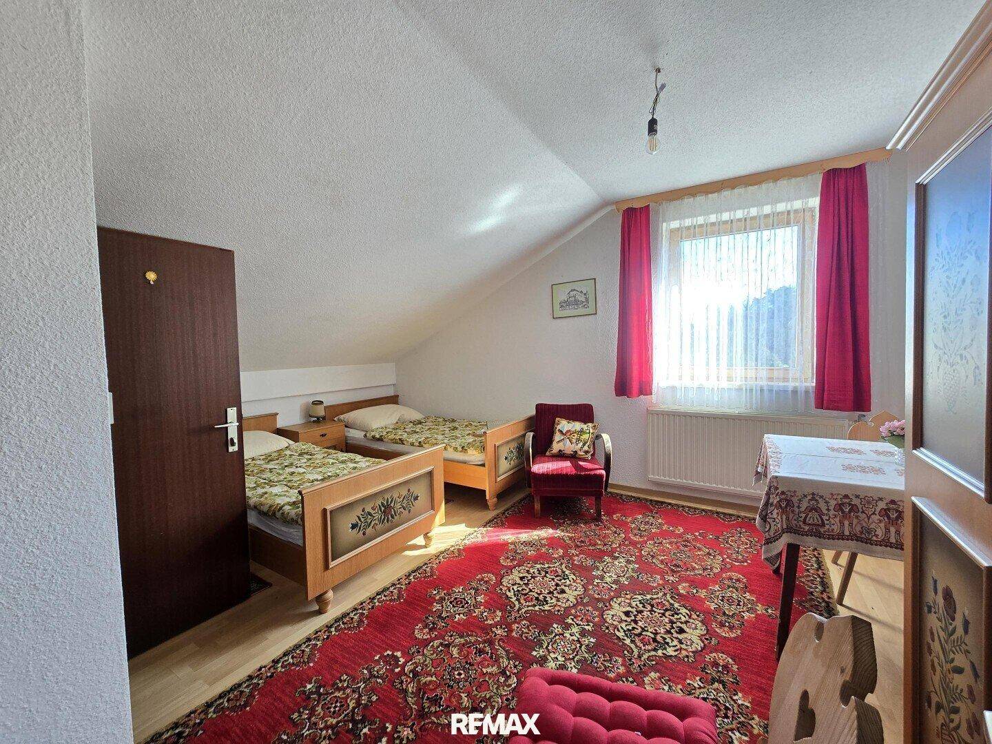 Schlafzimmer im Dachgeschoss mit zwei Einzelbetten und rotem Teppich.