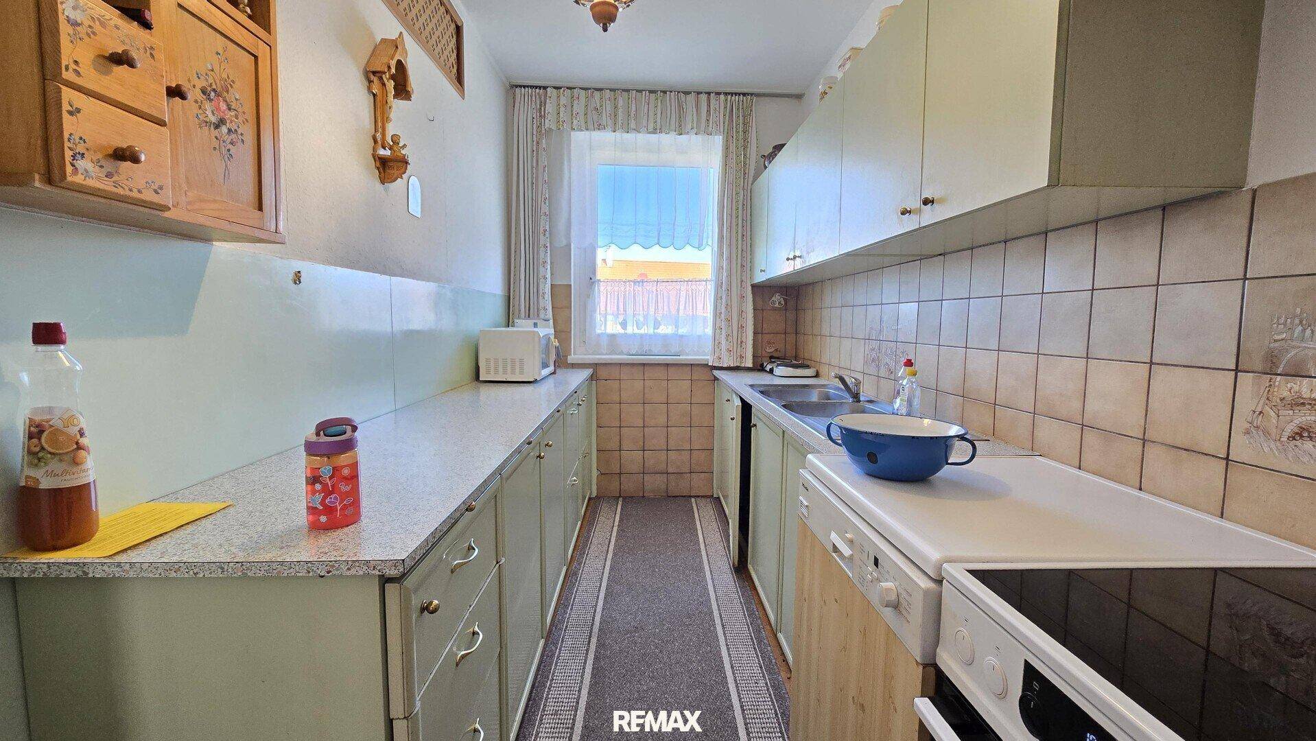 Funktionale Küche im Landhausstil mit hellgrünen Schränken und Fliesen.