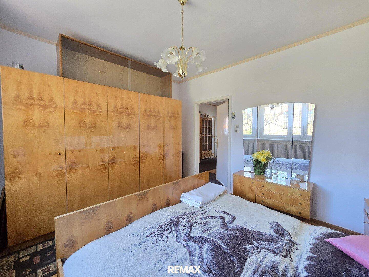Schlafzimmer mit Doppelbett, großem Holzschrank und Kommode mit Spiegel.
