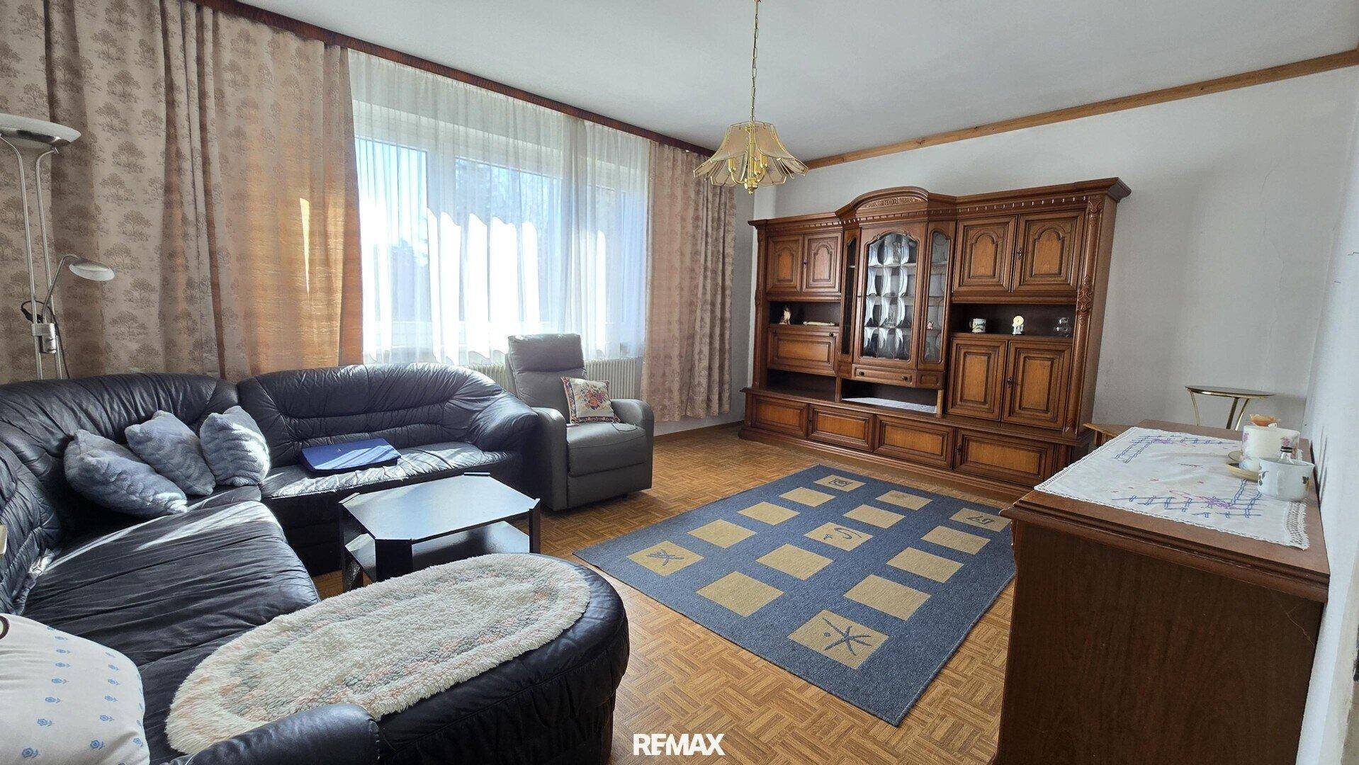 Gemütliches Wohnzimmer mit traditionellen Holzmöbeln und Teppichboden.