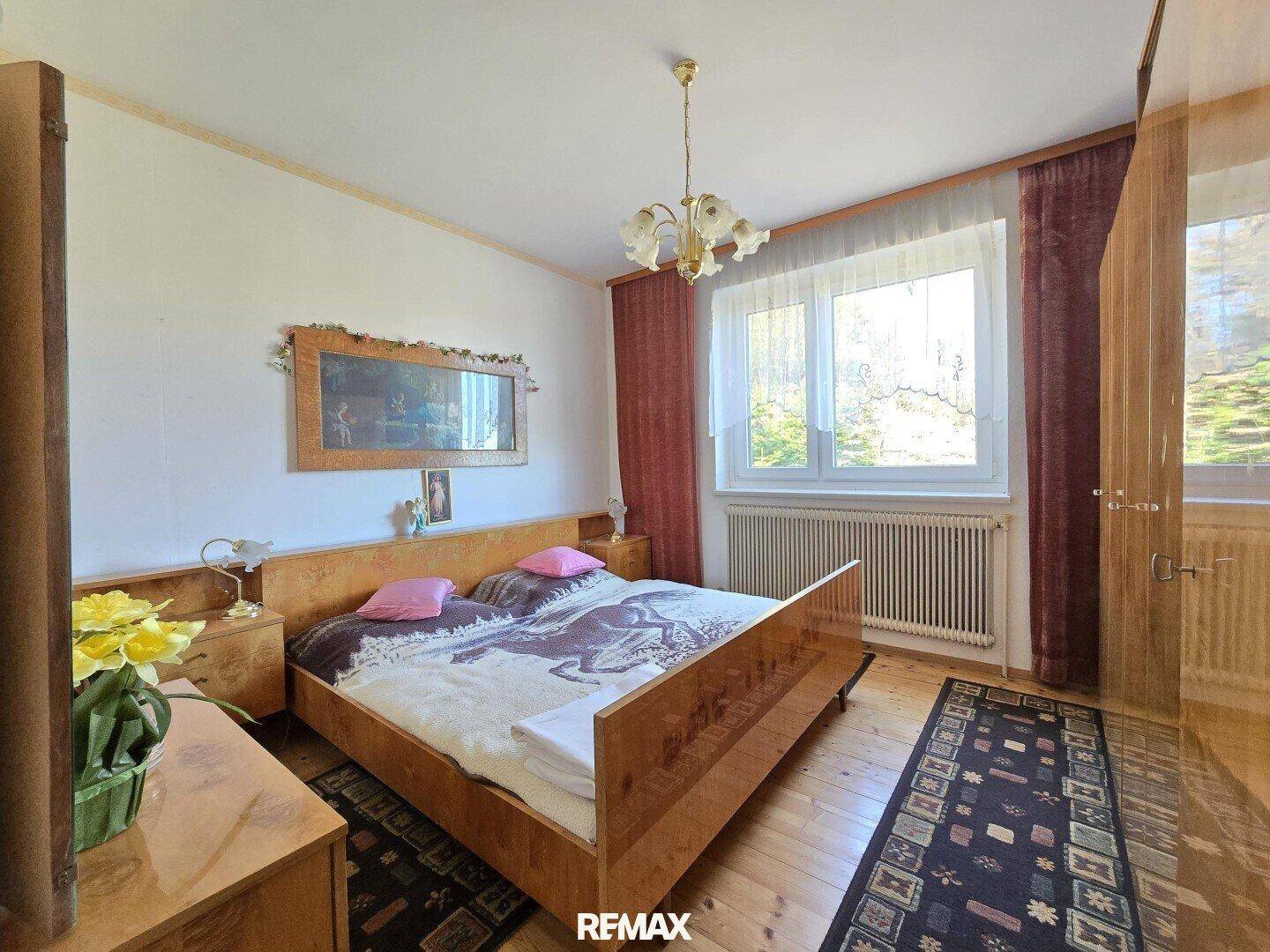 Gemütliches Schlafzimmer mit Doppelbett, Holzmöbeln und Blick ins Grüne.